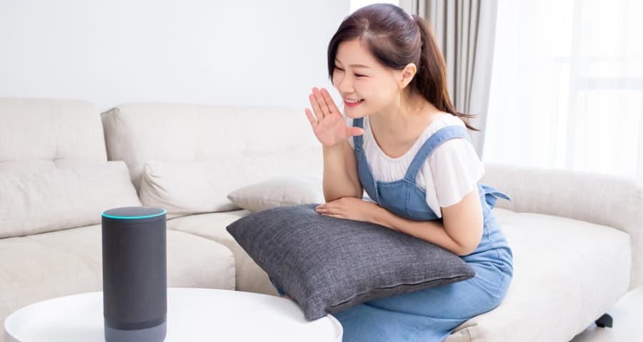 Young woman at home verbalizing a command to a smart speaker